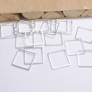 May include: A collection of silver-toned metal square frames, perfect for crafting jewelry or other DIY projects.
