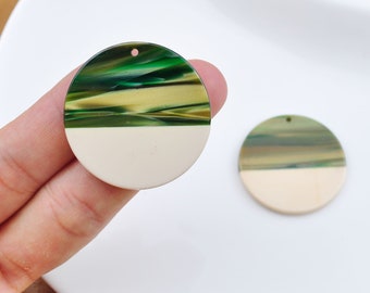 May include: Two round, green and white, resin, pendant charms with a hole at the top for hanging.