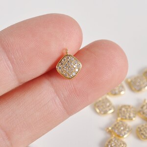 May include: Gold-toned pendant charm with a square shape and a pave setting of clear cubic zirconia stones.