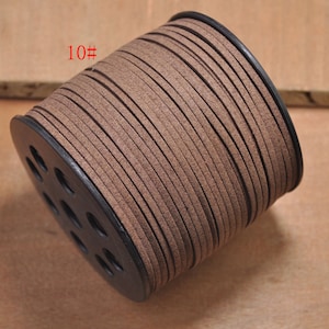 May include: A spool of brown suede cord, wound around a black plastic bobbin. The cord is approximately 10# in size.