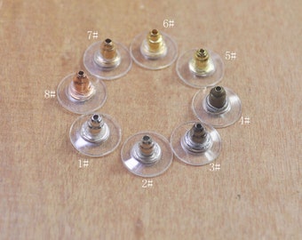 May include: Eight different colored earring backs, displayed on a wooden surface. Each back is on a clear plastic backing with a number from 1 to 8.