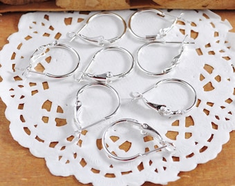 May include: A set of eight silver earring hoops with a lever back closure. The hoops are arranged on a white doily.