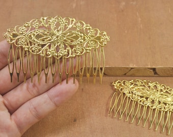 May include: Two gold metal hair combs with intricate floral designs. The combs have a decorative top and a row of teeth.
