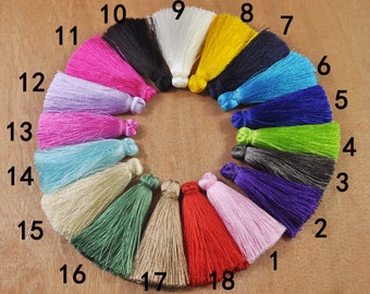 May include: A set of 18 colorful tassels arranged in a circle on a wooden surface. The tassels are numbered 1 through 18, with the numbers written in black.