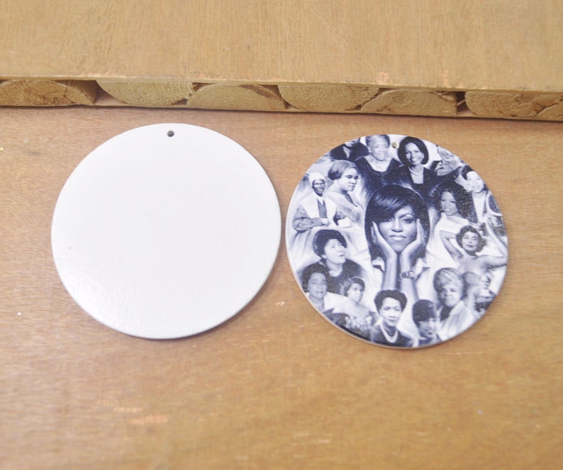 May include: Two round wooden ornaments, one blank and one with a collage of black and white photos of women. The photo ornament features a central image of a woman with her hands on her cheeks.