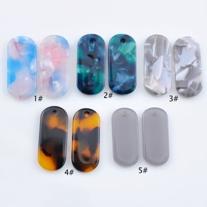 May include: Assortment of ten rectangular resin pendants with different patterns. The pendants have a hole at the top for hanging. The patterns include blue and white swirls, pink and white swirls, green and blue swirls, brown and black swirls, and grey.