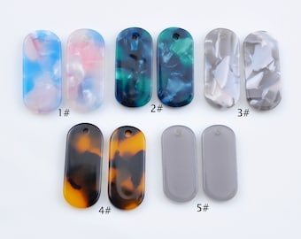 May include: Assortment of ten rectangular resin pendants with different patterns. The pendants have a hole at the top for hanging. The patterns include blue and white swirls, pink and white swirls, green and blue swirls, brown and black swirls, and gray.