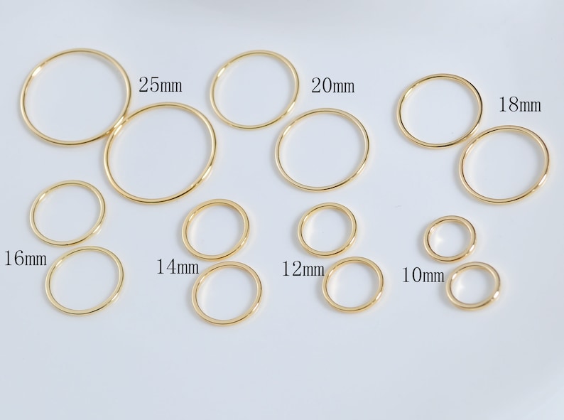 May include: Assortment of gold jump rings in various sizes, ranging from 10mm to 25mm.  The jump rings are arranged in rows on a white background.