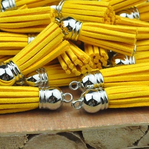 May include: A pile of yellow suede tassels with silver metal tops. The tassels are arranged in a random pattern and are all the same size.