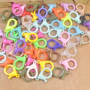 May include: A large assortment of colorful plastic lobster claw clasps. The clasps are in various colors, including red, blue, green, yellow, orange, pink, purple, and clear.