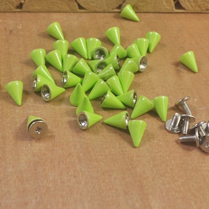 Op de afbeelding: Een groep van limoengroene, kegelvormige metalen studs met zilveren schroefbases. Er zijn 25 studs en 12 schroeven in de afbeelding.