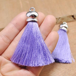 May include: Two purple silk tassels with silver metal caps. The tassels are approximately 2 inches long.