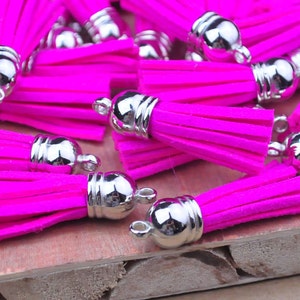 May include: A group of bright pink tassels with silver metal caps. The tassels are made of a soft, fuzzy material and are perfect for adding a touch of colour and texture to any project.