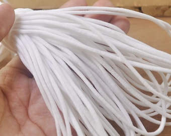 Peut inclure: Gros plan sur un paquet de cordon élastique blanc, souvent utilisé pour les masques faciaux ou d'autres travaux manuels.