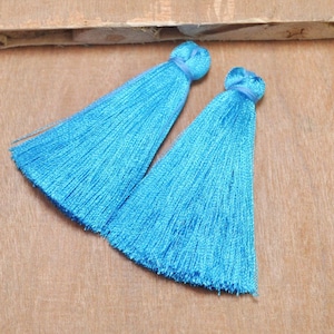 May include: Two bright blue silk tassels with a long fringe. The tassels are tied together at the top.