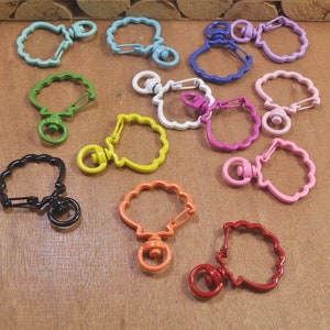 May include: Assortment of colorful metal keychains with scalloped edges. Each keychain features a different color and a swivel clasp.
