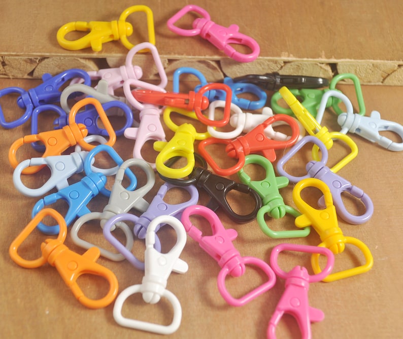 Puede incluir: Surtido de mosquetones de pl&aacute;stico giratorios de colores. Los mosquetones son de varios colores, incluyendo rojo, azul, verde, amarillo, naranja, rosa y morado.