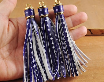 May include: Three blue and white star patterned leather tassels with gold metal tops.