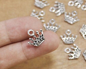 Puede incluir: Encantos de corona plateados con un bucle para sujetar a joyas o manualidades. Los encantos son pequeños y delicados, perfectos para agregar un toque de realeza a cualquier proyecto.