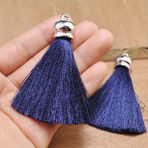Peut inclure: Deux glands de couleur bleu foncé avec des embouts en métal argenté. Les glands sont faits de fils doux et soyeux et mesurent environ 5 cm de long.