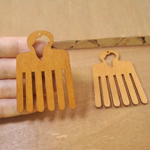 May include: Two wooden combs with a traditional African design. The combs are brown and have a rounded top.