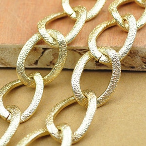 May include: Gold chain with textured links. The chain is made of metal and has a shiny finish.