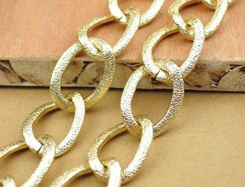 May include: Gold chain with textured links. The chain is made of metal and has a shiny finish.