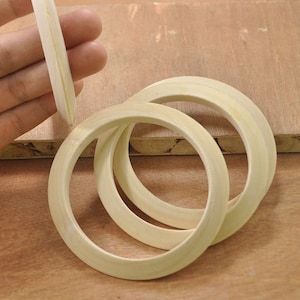 Peut inclure: Trois anneaux en bois, imbriqués les uns dans les autres, de couleur bois naturel. Les anneaux sont ronds et ont une surface lisse.
