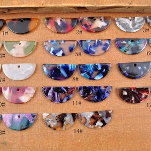 May include: Assortment of 14 pairs of colorful, patterned, half-circle shaped resin cabochons with holes for jewelry making.