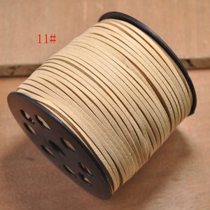 Op de afbeelding: Een spoel beige lederen koord, gewikkeld om een zwarte plastic spoel met een label met de tekst "11#"