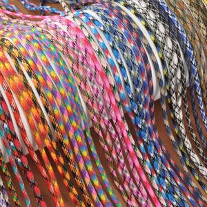 May include: A collection of colorful paracord ropes in various patterns and colors, including red, orange, blue, pink, and green. The ropes are tightly woven and appear to be new, with a variety of designs.