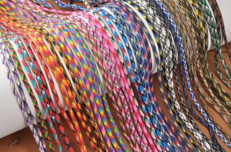 May include: A collection of colorful paracord ropes in various patterns and colors, including red, orange, blue, pink, and green. The ropes are tightly woven and appear to be new, with a variety of designs.