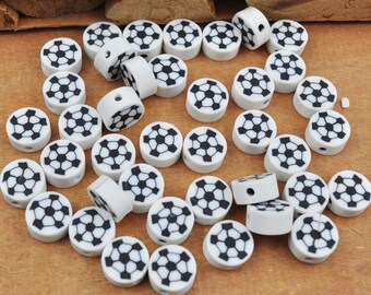 Può includere: Una collezione di perline in ceramica bianca con un design a pallone da calcio nero. Le perline sono rotonde e hanno un foro al centro per essere infilate.
