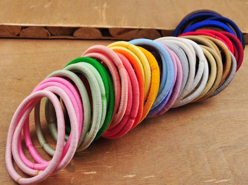K&ouml;nnte beinhalten: Eine gro&szlig;e Auswahl an bunten Haargummis in verschiedenen Farbt&ouml;nen von Rosa, Gr&uuml;n, Blau, Gelb, Orange, Rot und Braun. Die Haargummis sind aus einem weichen, dehnbaren Material gefertigt und perfekt, um das Haar an Ort und Stelle zu halten.