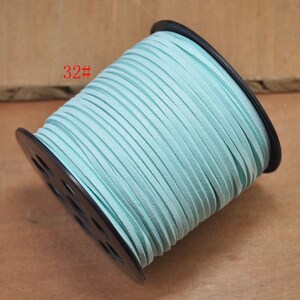 May include: A spool of light blue suede cord, labeled "32#", is wound around a black plastic spool.