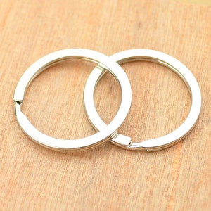 May include: Two silver key rings interlocked together on a wooden surface.