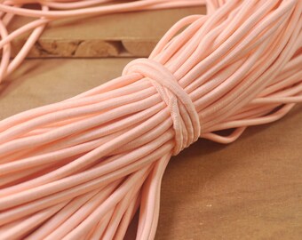 May include: A close-up of a large bundle of peach-colored elastic cord. The cord is soft and flexible, and it is perfect for crafting projects.