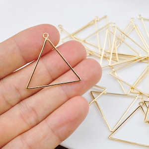 Peut inclure: Un tas de cadres en métal de forme triangulaire de couleur dorée avec une boucle en haut. Les cadres mesurent environ 3,8 cm de long.