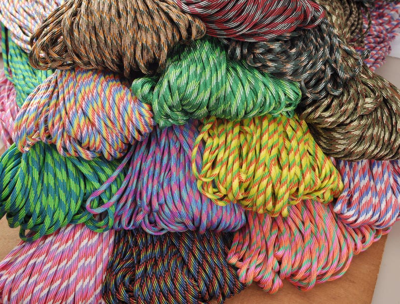 May include: A collection of colorful paracord bundles in various shades, including green, yellow, blue, pink, and brown. The cords are tightly wound, showcasing a variety of patterns and color combinations. The image is a close-up, highlighting the texture and detail of the cords.