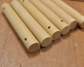 Peut inclure: Six chevilles en bois avec des trous percés au centre. Les chevilles sont disposées en rangée, les extrémités des chevilles étant face au spectateur.