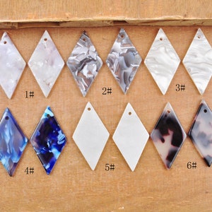 May include: Six different diamond-shaped resin pendants with various patterns. The pendants are numbered 1 through 6. The patterns include white, black, blue, and brown.