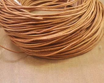 May include: A close-up of a spool of brown leather cord. The cord is tightly wound and has a rough texture.