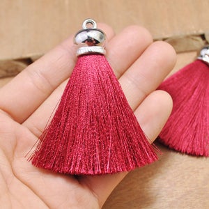 May include: Two red silk tassels with silver metal caps. The tassels are soft and fluffy.