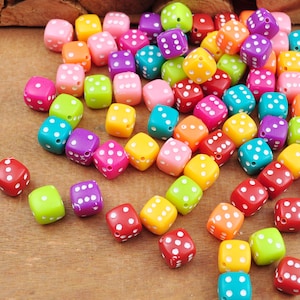Può includere: Un grande gruppo di dadi colorati con punti bianchi. I dadi sono di plastica e sono sparsi su una superficie di legno.