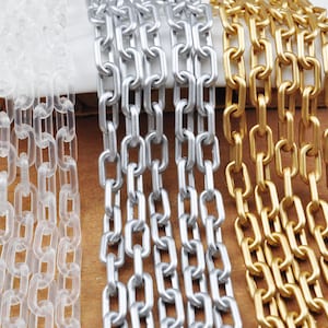 Puede incluir: Tres hebras de cadena, una de plástico transparente, una de plata y una de oro. Las cadenas son todas del mismo estilo, con eslabones ovalados.