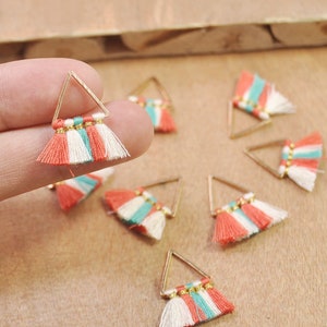Puede incluir: Charms de pendientes de forma triangular dorada con borlas de coral, blanco y turquesa.
