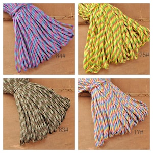 May include: Four bundles of colorful paracord rope. One bundle is blue, pink, and purple. Another is yellow, green, and red. The third is green, brown, and tan. The last is blue, yellow, and red. Each bundle has a number on it.