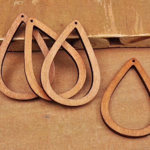 Puede incluir: Cuatro blanks de pendientes de madera sin terminar en forma de lágrima. Los blanks miden aproximadamente 5 cm de largo y tienen un agujero en la parte superior para sujetar los hallazgos de los pendientes.