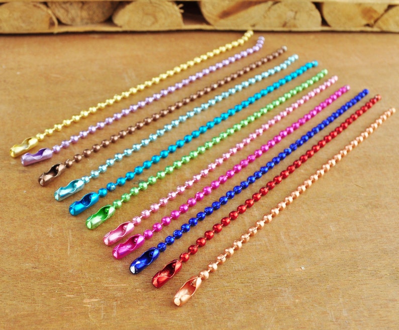 May include: Assortment of 14 colourful metal chain links with a beaded design. The chains are arranged in a row from lightest to darkest colour, starting with gold and ending with copper.