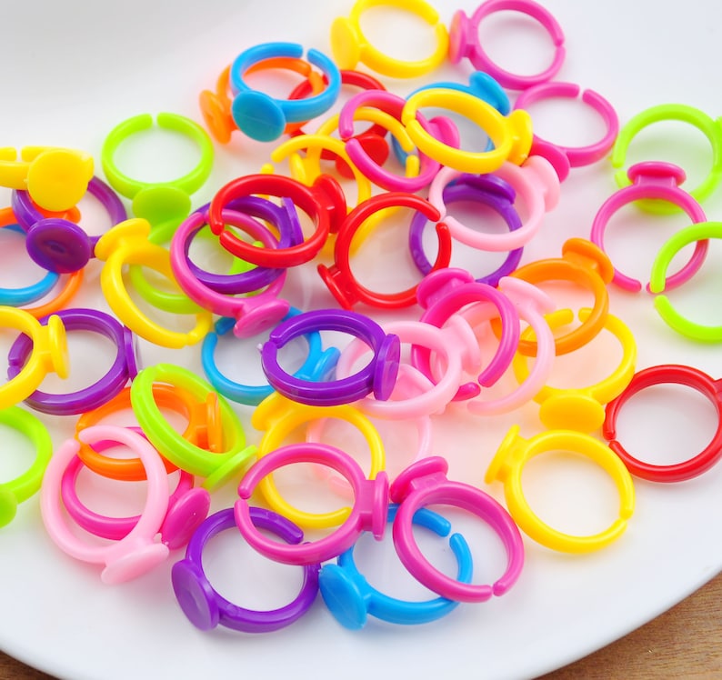May include: A collection of colorful plastic rings with a flat, round base. The rings are in various colors, including red, orange, yellow, green, blue, purple, and pink.